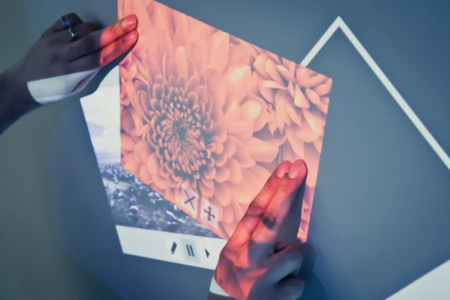 Hands manipulating a projected photo interface on a wall