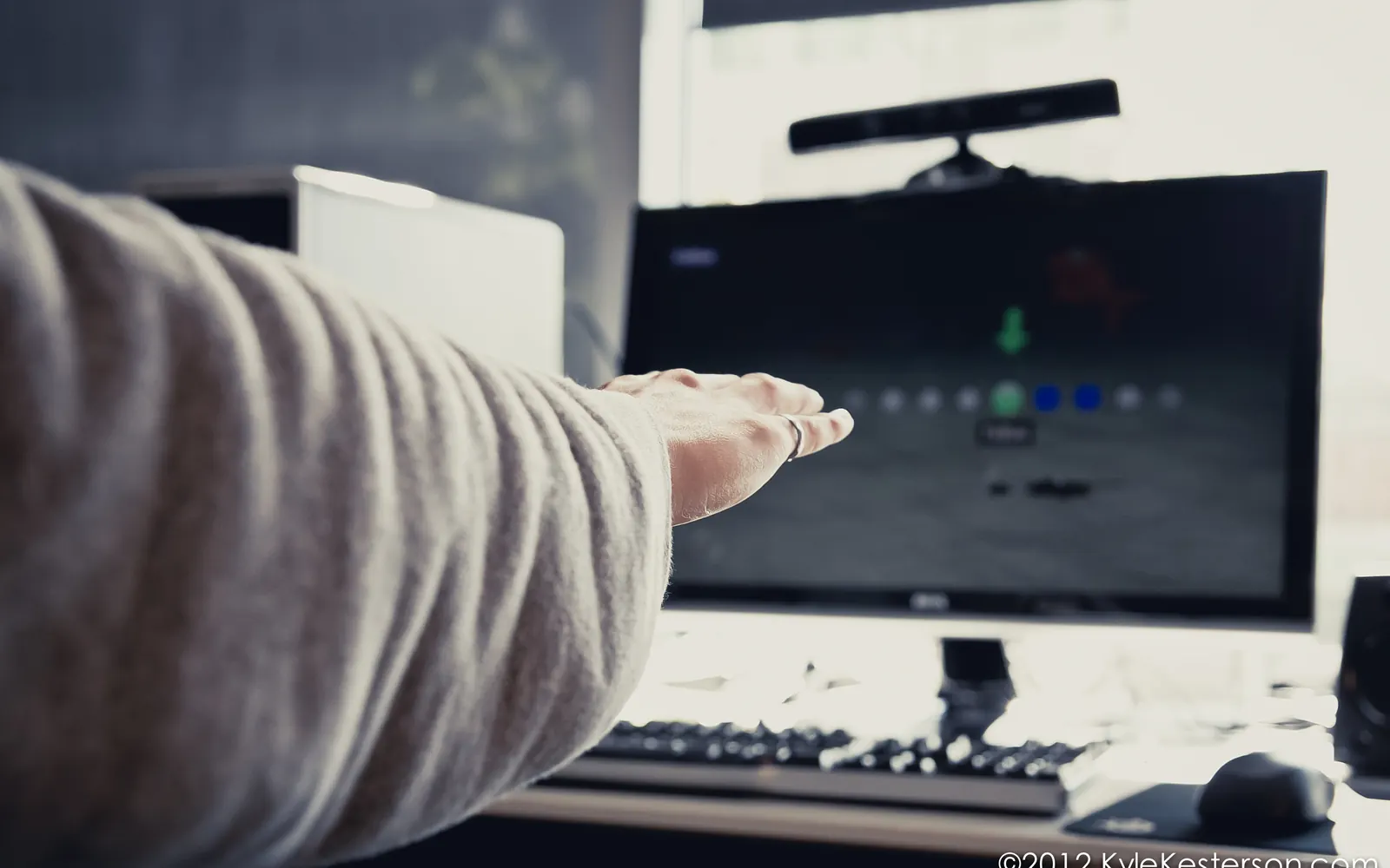 A hand reaching toward a Kinect sensor, tracking on the monitor