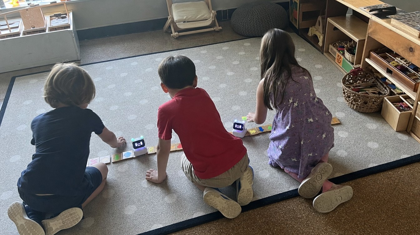 Three kids from above and behind laying tiles on a rug, bots driving