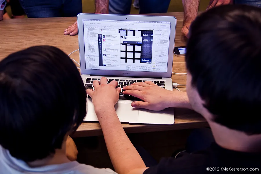 Two students pair-programming on a laptop, seen from above